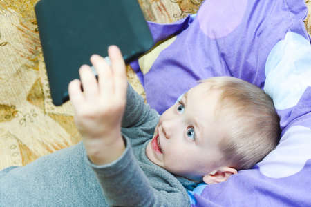 Little boy playing on the couch in the tabletの写真素材