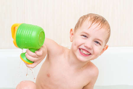 little boy bath in a bathtub with a toyの写真素材