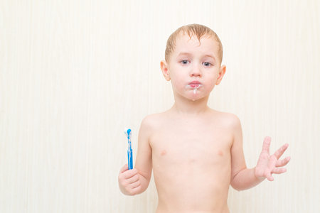 Small handsome boy brushing his teeth blue brush in the bathの写真素材