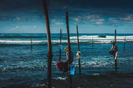 WELIGAMA, SRI LANKA - March 04 2017: Fishermen sit on their stilts waiting for shoal of fish to catch them. An old tradition, that is only seen, on the south coast, of Sri Lankaのeditorial素材