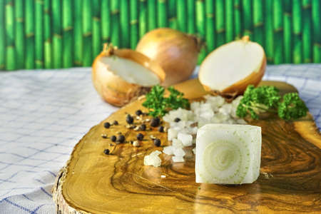 onion cube on a wooden cutting board with pepper and parsleyの写真素材