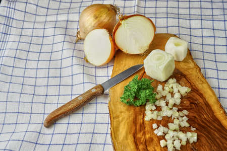 onion on a wooden cutting board with a knife, pepper and parsleyの写真素材