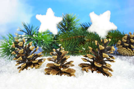 Three pine cones in the snow with a pine branch and two stars from snow in the background, narrow depth of fieldの写真素材