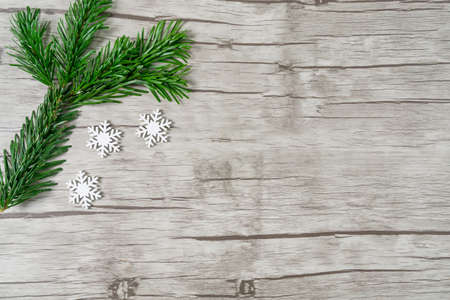 Branch of a fir tree with little snowcrystals on wooden background with copy spaceの写真素材