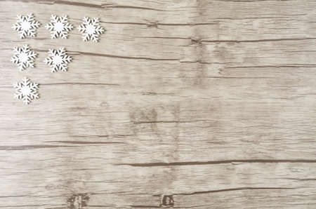 Six whitewooden snowcrystals in the top left corner on wooden background with copy spaceの写真素材