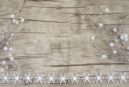 Bright wooden board with decorative white snowcrystals at the bottom picture edge and at the sides decorative branches with white ballsの写真素材