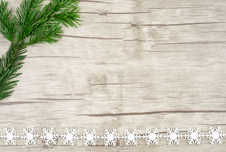 A pine branch on the right side of the picture and at the bottom picture snowcrystals on wood, wooden background and copyspaceの写真素材
