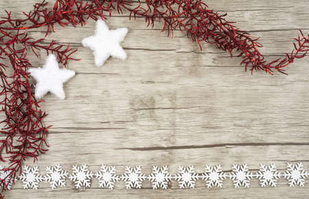 Red glittering twig with two snow stars in the left corner on wooden background with decorative snowcrystals of wood at the bottom pictured copyspaceの写真素材