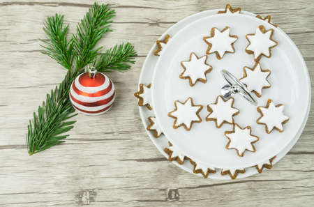 A plate of cinnamon stars, beside it a christmas ball and a pine branchの写真素材