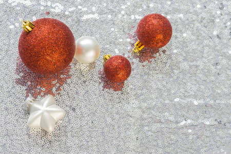 Christmas decorations on silver fabric with sequins, three red balls in different sizes, a white matt glossy finish star and a little ball, copyspaceの写真素材