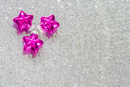 Christmas decorations on silver fabric with sequins, three pink colors stars in the upper left corner, copyspaceの写真素材