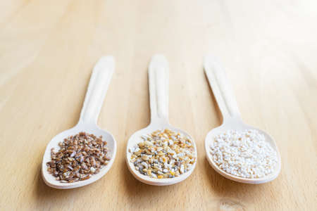 Superfood, three wooden spoons with crushed linseed, amaranth and quinoa, on a background of wood, copyspaceの写真素材