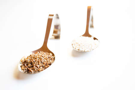 Superfood, two silver spoons with bent stem, crushed linseed and amaranth on white backgroundの写真素材