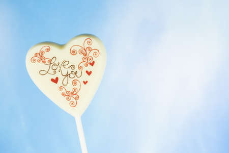 Chocolate heart with the inscription Love you, blue sky backgroundの写真素材