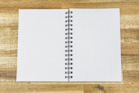 Opened notebook with squared lines, wooden background