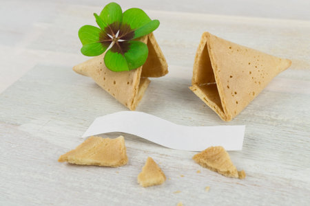 Broken fortune cookie with blank label and four-leaf clover, wooden backgroundの写真素材