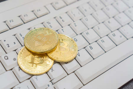 Three bitcoins on computer keyboardの写真素材