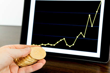 Tablet with a chart and a hand with bitcoinsの写真素材