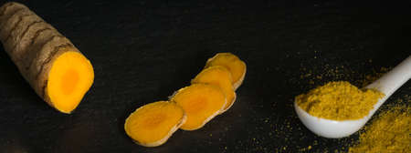 Turmeric root and powder on black backgroundの写真素材