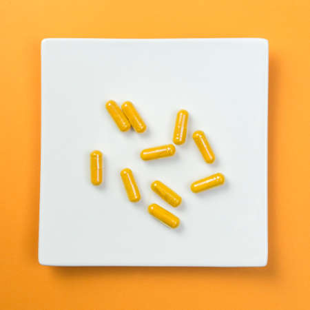 Yellow vitamin pills on orange backgroundの写真素材
