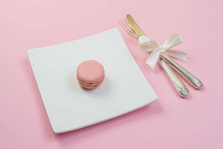 Silver fork with white ribbon and plate on a pink backgroundの写真素材