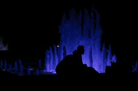 Fountain in the night with people silhouettesの写真素材