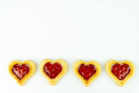A row with fresh baked heart shaped cookies, white bakcground and copy space