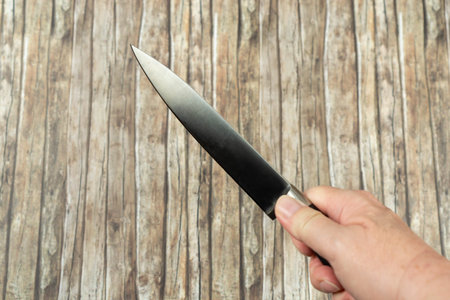 Butchers knife holding in hand, wooden background