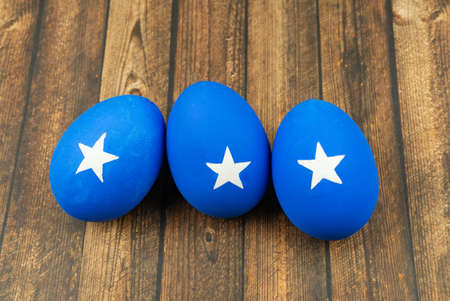Blue easter eggs with white stars on wood backgroundの写真素材