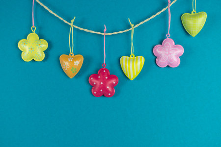 Colorful decoration pendant in heart and flower shape on a cord, blue background and copy space