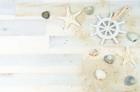 Maritime background with sand, shells and an old white wooden wheelの写真素材