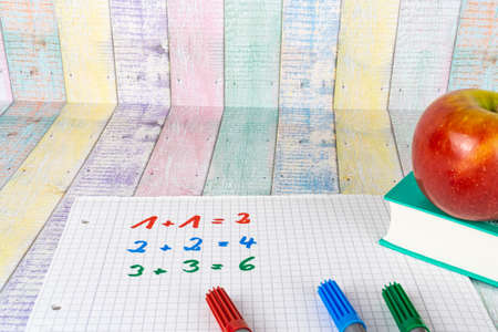 A block with simple calculating tasks and an apple fruit, colorful wood background and copy spaceの写真素材