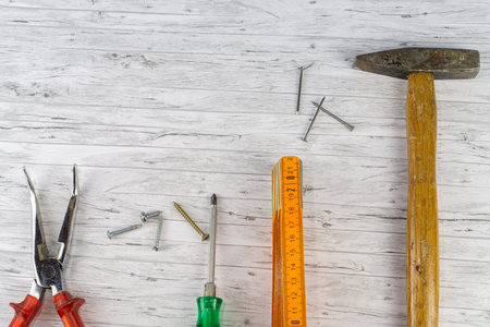 Hand tools on a white wooden background, hammer with nails and a folding rule, next to it a...