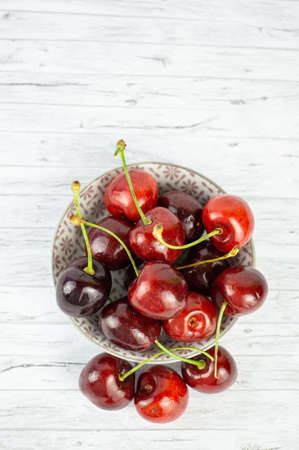 A bowl with fresh cherries on white wooden table, copy spaceの写真素材