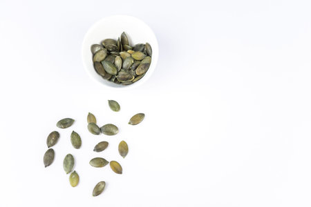 A cup with pumpkin seeds on white background with copy space