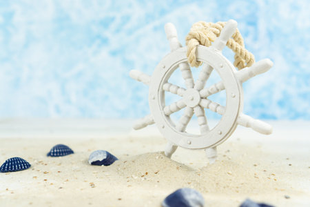 Maritime background with sand, shells and an old white wooden wheel