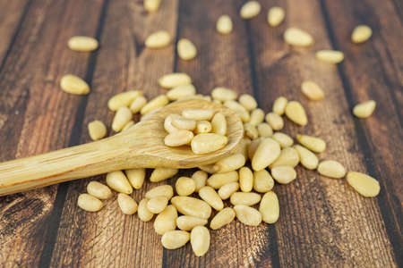 Many pine nuts with wooden spoon and wooden backgroundの写真素材