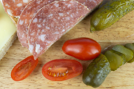 A slice of bread with salami and a slice of bread with cheese, while still small cocktail tomatoes...