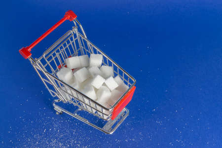 A shopping cart with sugar cubes, blue background and copy spaceの写真素材