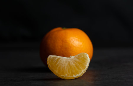 A mandarin and a piece of mandarin, black background