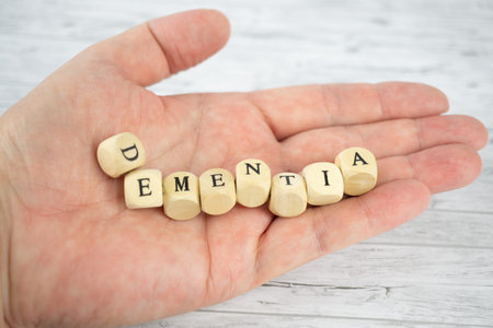 Hand with wood cubes and the inscription dementia, wooden backgroundの写真素材