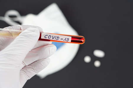Hand with a laboratory tube with blood sample and the imprint Covid-19の写真素材