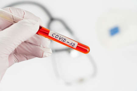 Hand with a laboratory tube with blood sample and the imprint Covid-19の写真素材