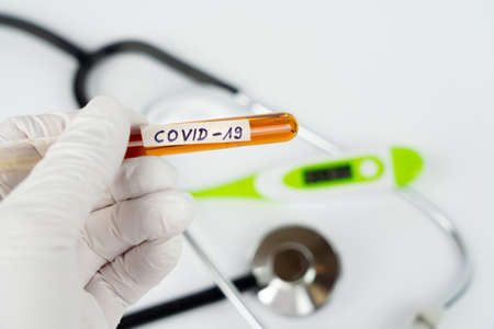 Hand with a laboratory tube with blood sample and the imprint Covid-19の写真素材