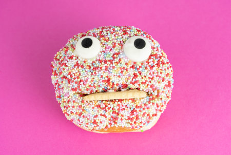 Delicious cake with funny face, pink background