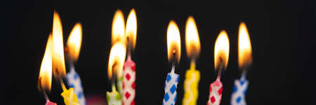 Many burning colorful birthday candles, black background with copy spaceの写真素材