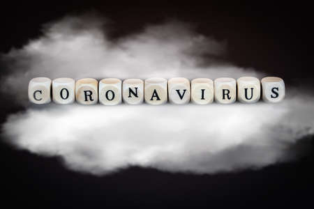 The word coronavirus in wooden cubes on a cloud, black backgroundの写真素材