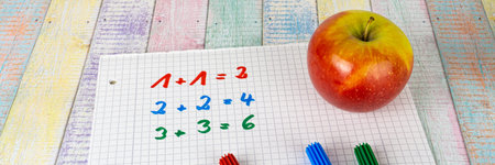 A block with simple calculating tasks and an apple fruit, colorful wood background and copy space,...