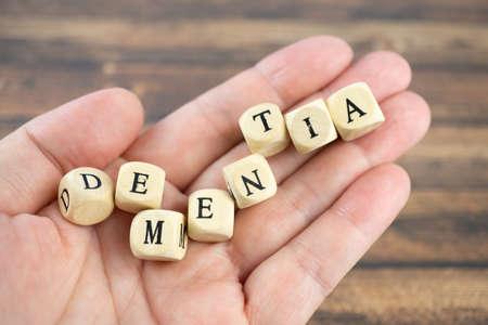 Hand with wood cubes and the inscription dementia, wooden backgroundの写真素材