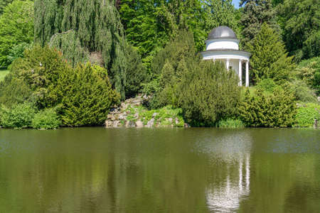 Small white temple in a park in front of a pondの写真素材